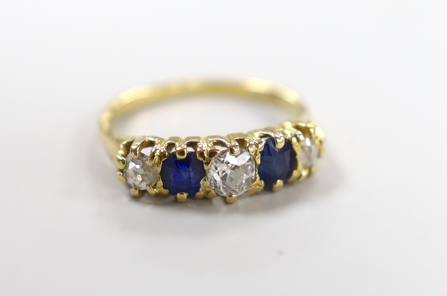 An 18ct, three stone diamond and two stone sapphire set half hoop ring, size M, gross weight 3.3 grams.
